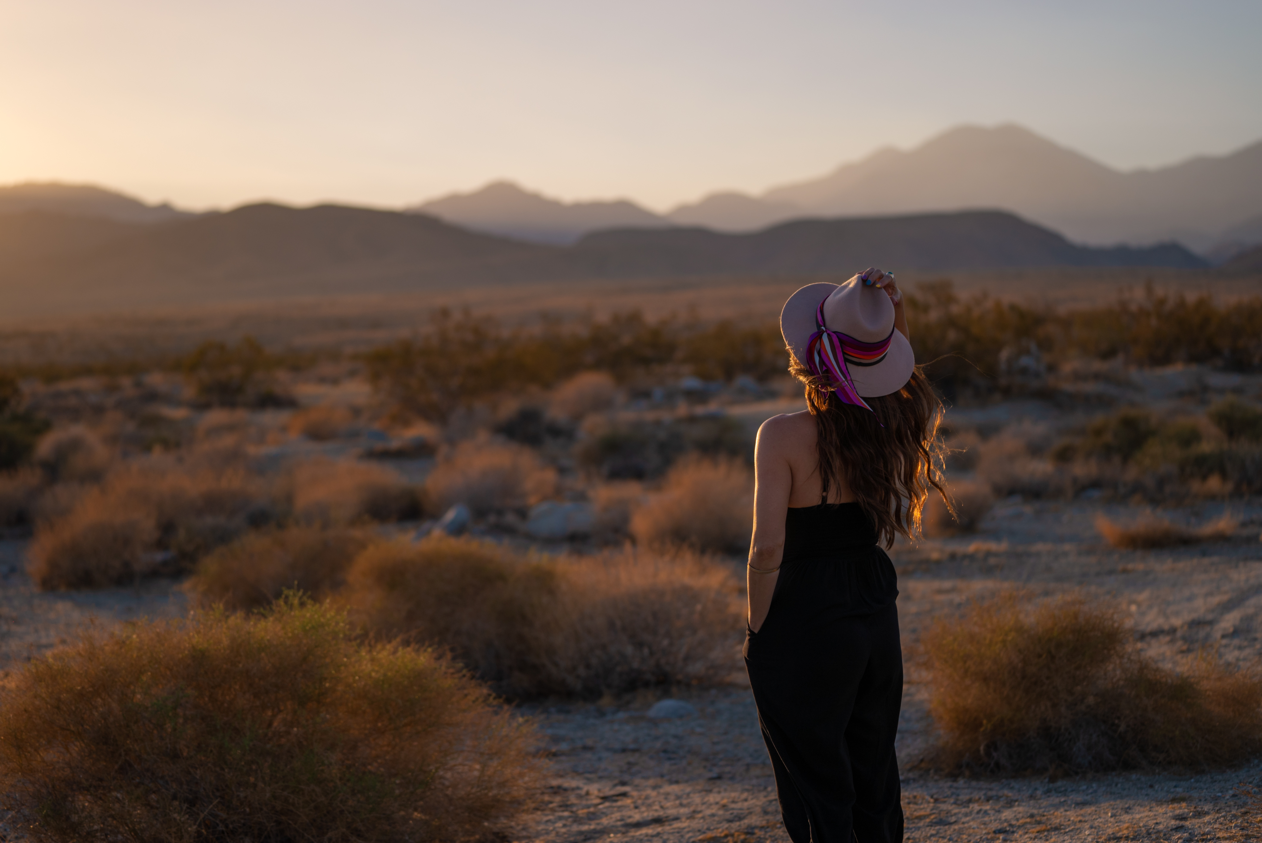 Anndee gazing at the sunset in the desert, surrounded by mountains.